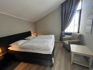 a bedroom with a bed and a chair and a window at Aquaronde 108 in Lemmer