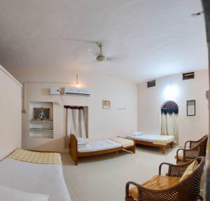 a room with two beds and chairs in it at Sri Anantha Niketan Ashram in Tiruvannāmalai
