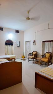 a room with two beds and two chairs in it at Sri Anantha Niketan Ashram in Tiruvannāmalai