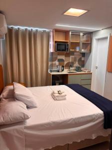 a bedroom with a large bed and a kitchen at Suites Coliseu 40-A in Petrolina