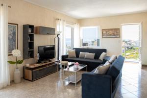 a living room with a couch and a tv at Oasis Sea view suit in Agia Marina Mikrolimanou