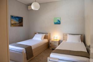a bedroom with two beds and a lamp on a table at Oasis Sea view suit in Agia Marina Mikrolimanou +43 photos