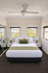 a white bedroom with a large bed and windows at Emerald Inn by Travellers in Emerald