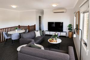 a living room with two couches and a tv at Emerald Inn by Travellers in Emerald