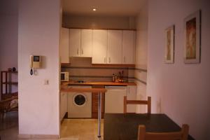 cocina con armarios blancos, lavadora y secadora en Apartamento Judería Lirio alto, en Sevilla