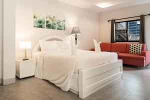 a white bedroom with a white bed and a red couch at Secret Corner Boutique Stay in Chiang Rai