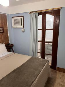 a bedroom with a bed and a window with a fan at Pousada Luar e Serenata in Conservatória