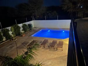 a swimming pool at night with chairs and a swimming pool at Le Refuge, Residence Ibrahima in Rufisque