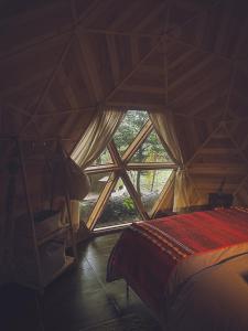 a room with a bed and a large window at Lodge Domos Awen in Pucón