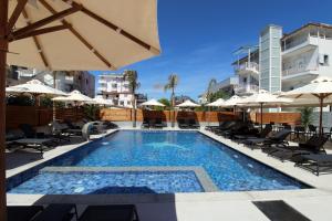 a swimming pool with chairs and umbrellas on a building at Hotel Villa Kapo Pool & Bar in Ksamil