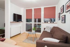 a living room with a couch and two windows at ShortStayPoland Graniczna (B6) in Warsaw