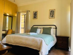 a bedroom with a large bed with green pillows at The Folkestone Guest House in Gqeberha +45 photos