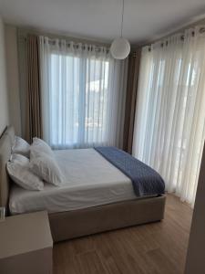 a bedroom with a bed with white pillows and windows at Villa Gala - First Floor Apartment in Draç