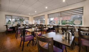 a dining room with tables and chairs and windows at Hotel-Pension Ouddorp in Ouddorp