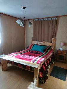 a bedroom with a wooden bed with a colorful blanket at Puñañas descanso y experiencias in Vilcún