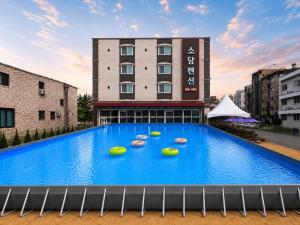 a large blue swimming pool in front of a building at Daecheon Sodam pension in Boryeong