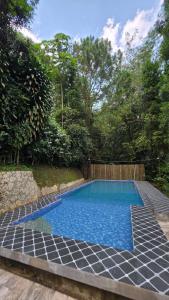 a swimming pool with blue water in a yard at Villa Arkhazio in Megamendung
