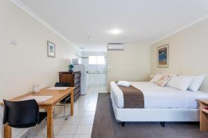 a bedroom with a bed and a desk and a table at Emu Point Motel in Albany