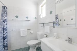 a white bathroom with a toilet and a sink at Emu Point Motel in Albany +30 photos