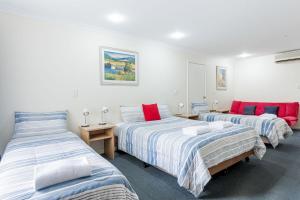 two beds in a room with white walls and red accents at Emu Point Motel in Albany