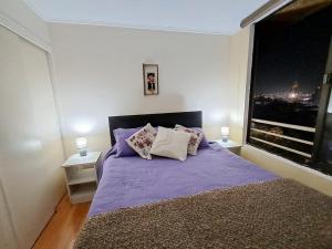 a bedroom with a purple bed with a large window at Acogedor y amplio departamento central in Temuco