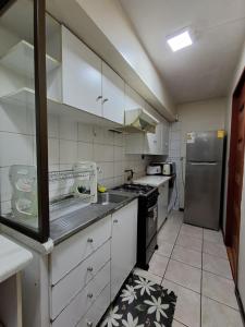 a kitchen with white cabinets and a stainless steel refrigerator at Acogedor y amplio departamento central in Temuco