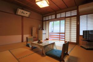 a living room with a table and chairs and a refrigerator at Ougiya Ryokan in Toyooka