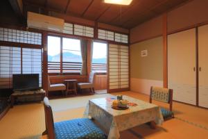a living room with a television and a table and chairs at Ougiya Ryokan in Toyooka +16 photos