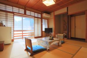 a living room with a table and a tv at Ougiya Ryokan in Toyooka