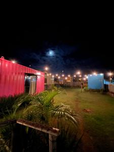 a red building with lights in a field at night at POUSADAGiraGarden Containers in Arroio do Silva