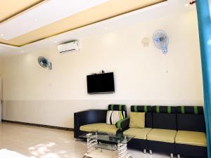 a living room with a couch and a tv on a wall at The Red Hotel Côn Đảo in Con Dao