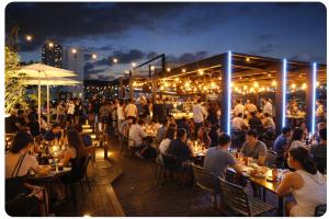 a crowd of people sitting at tables on a patio at night at Brosis Hotel in Busan