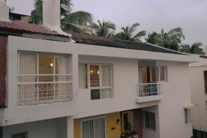 a white building with palm trees in the background at Azure Luxury 3-Bedroom Penthouse Candolim, Next to Novotel and Starbucks, close to Beach - By Lembranca in Candolim