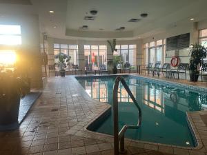 a swimming pool in a hotel with chairs and tables at Hilton Garden Inn Montreal Airport in Dorval