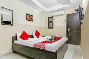 a bedroom with a bed with red pillows at Hotel O Royal Green in New Delhi