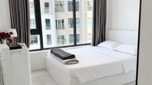 a white bedroom with a bed and a large window at 1932 OC2a in Nha Trang