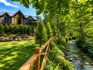 a house with a wooden fence next to a river at Villa Vrosi - فلل وأكواخ فيروز السياحية in Ardeşen