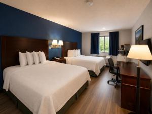ein Hotelzimmer mit zwei Betten und einem Schreibtisch in der Unterkunft Corning Inn in Painted Post