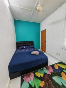 a bedroom with a bed with a blue wall at wawa homestay in Butterworth