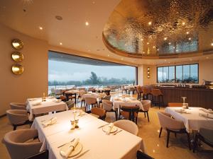 a restaurant with white tables and chairs and a large window at Sole Mio Boutique Hotel and Wellness - Adults Only in Bang Tao Beach