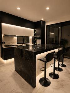 a kitchen with a black counter and black stools at Casa Luna con alberca privada y billar in Cuautla Morelos