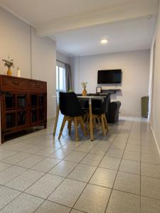 a living room with a table and chairs and a television at Dpto del Cerro in Tandil +3 photos