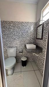 a bathroom with a toilet and a tiled wall at cantinhoannajullyaatins in Atins