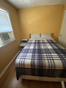 a bedroom with a bed with a plaid blanket and a window at Va Beach Town Center Privita Room in Virginia Beach