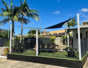 a fence with a table in a yard with palm trees at Nambour Heights Motel in Nambour