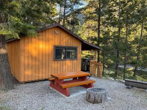 a wooden cabin with a picnic table in front of it at Doug's Emporium and Riverside Cabins in Hedley