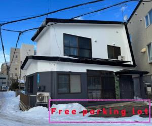 a white and black house with a free parking lot at Goryokaku rental house SAKURA in Hakodate