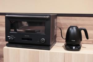 a black microwave with a tea kettle on a counter at 御宿 凪ぐ Takayama in Takayama