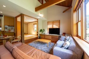 a living room with a couch and a tv at CALL92Chalet in Hakuba