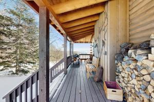 a wooden porch of a cabin with a stack of logs at North Hill Cabin in Jay
